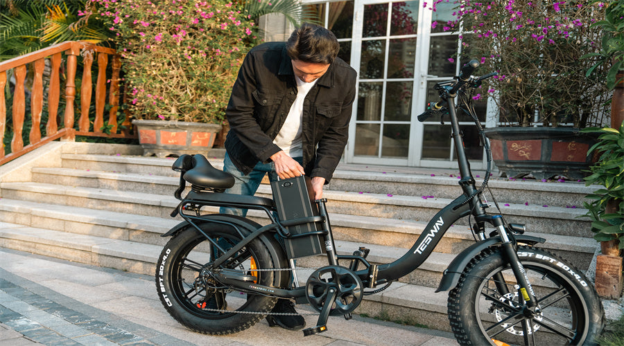 A man in black removes the battery from a Tesway s5 folding electric bicycle