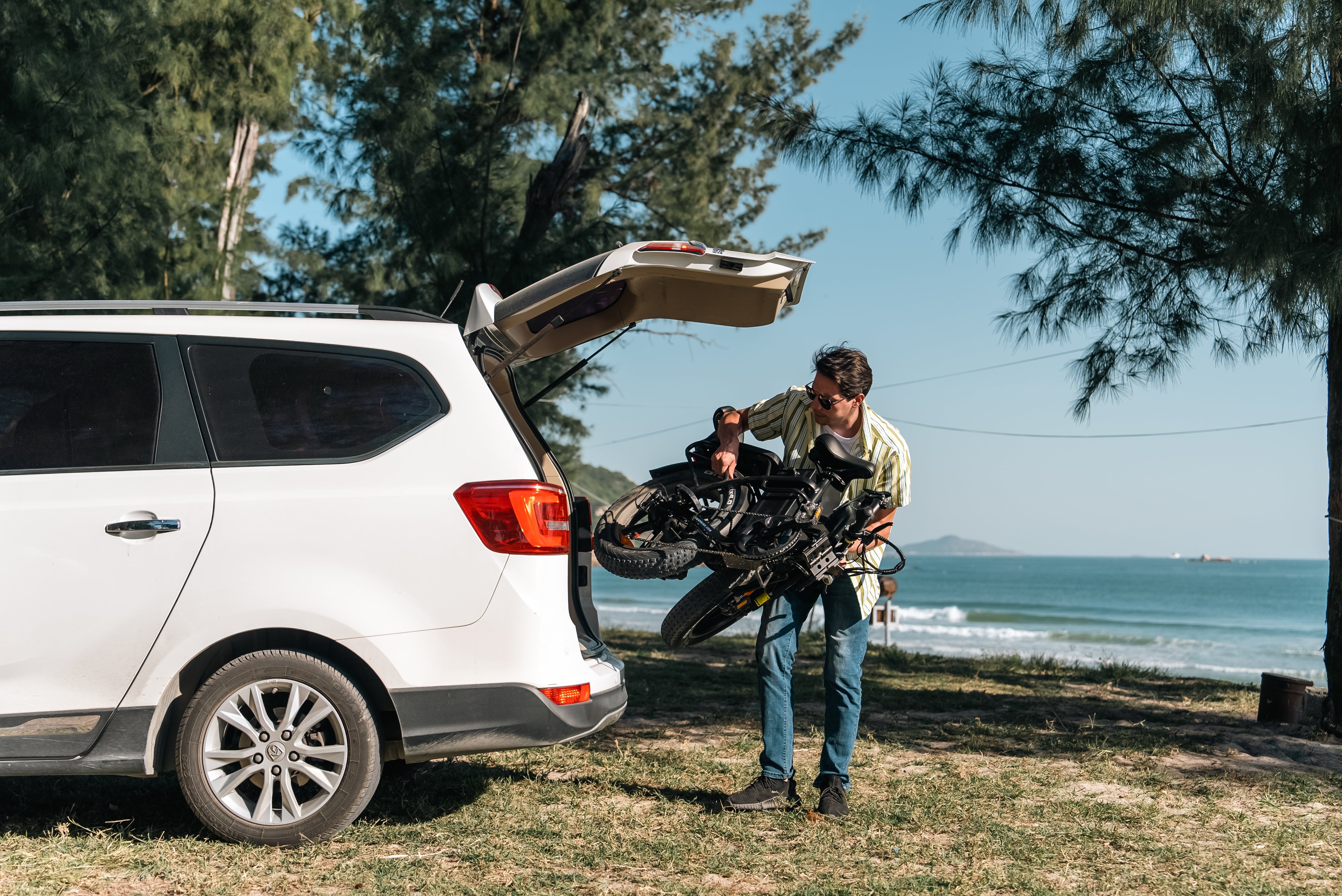 A man in a white shirt puts a foldable Ebike tesway s5 into the trunk of his car